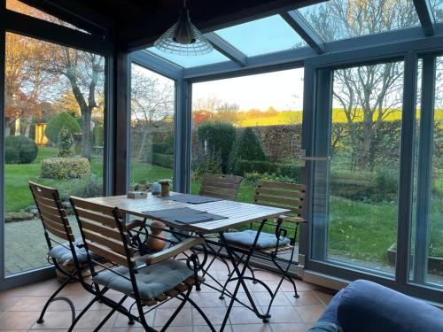 a conservatory with a table and chairs in a room with windows at Haus-Hoeppches in Blankenheim