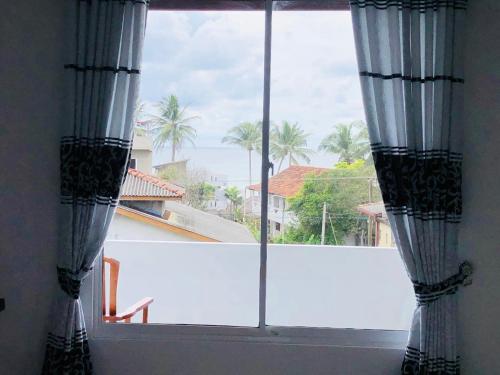 a window with curtains and a view of a balcony at Indika's Apartment in Hikkaduwa