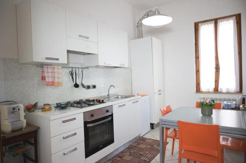 una cocina con armarios blancos y una mesa con sillas naranjas en La casa di Emma, en Terni