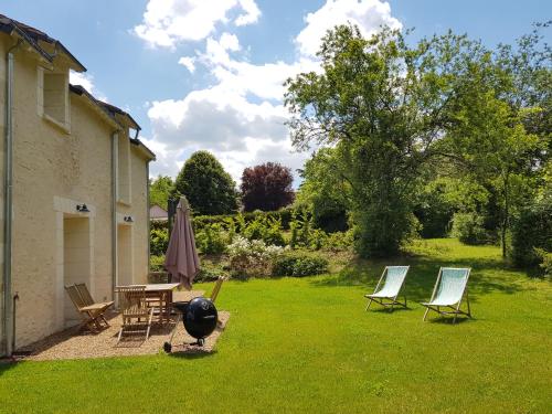 - une cour avec des chaises, un grill et un parasol dans l'établissement Le Domaine des Cyclamens, à Verneuil-sur-Indre