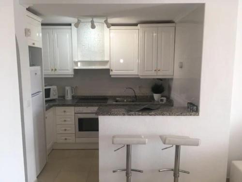 een keuken met witte kasten en een aanrecht met krukken bij Casa JC in Orihuela