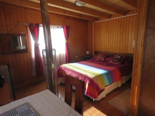 1 dormitorio con 1 cama en una habitación de madera en Hostal y Cabañas Perla del Lago, en Puerto Guadal