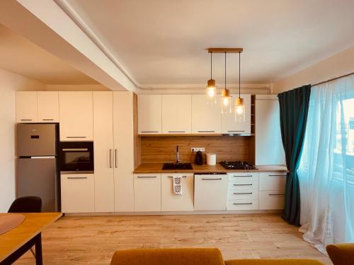 uma cozinha com armários brancos e uma mesa em A&Y APARTAMENT em Floreşti