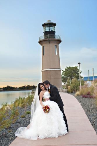 a bride and groom kissing in front of a lighthouse at Clover Island Inn in Kennewick