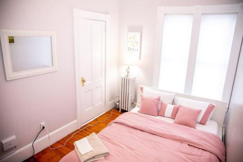 a bedroom with a bed with pink sheets and a window at 521 Smith Steet LLC in Providence
