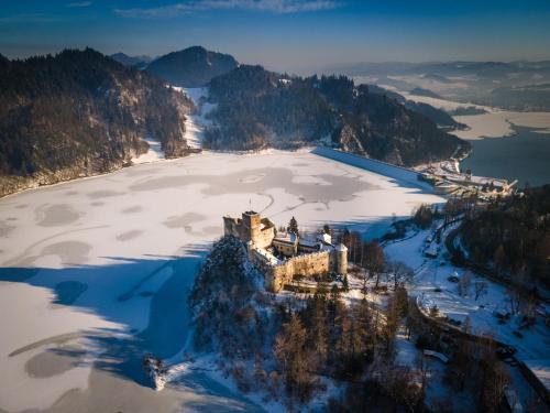 an aerial view of a castle on an island in the snow at REZYDENCJA SPISZ dom 12 osób, podgrzewany basen, sauna, jacuzzi- velo Czorsztyn, Niedzica in Niedzica Zamek