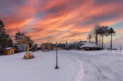a snow covered street with a sunset in the sky at REZYDENCJA SPISZ dom 12 osób, podgrzewany basen, sauna, jacuzzi- velo Czorsztyn, Niedzica in Niedzica Zamek