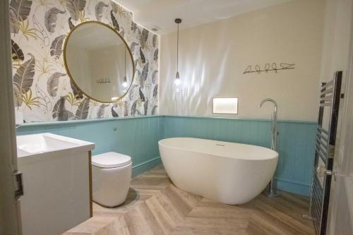 ein Badezimmer mit einer Badewanne, einem Waschbecken und einem Spiegel in der Unterkunft The Loft Winchester in Winchester