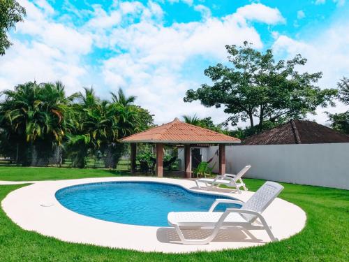 a swimming pool with two chairs and a gazebo at CORONADO VILLA VICTORIA in San Carlos