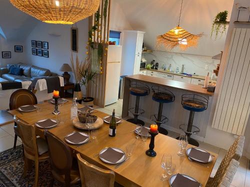 a large wooden table with chairs and a kitchen at La petite duchesse - jaccuzzi in Plérin