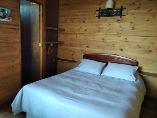 1 dormitorio con cama blanca y pared de madera en Terrazas de Laguna Verde, en Laguna Verde