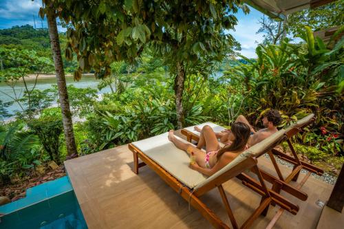 a man and a woman sitting in lounge chairs on a patio at El Jardin Lodge & Spa in Puerto Misahuallí