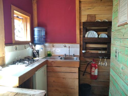 uma cozinha com um lavatório e uma parede vermelha em Terrazas de Laguna Verde em Laguna Verde