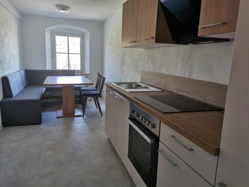 a kitchen with a stove and a table with a couch at Ferdlhof Ferienwohnung in Ulrichsberg