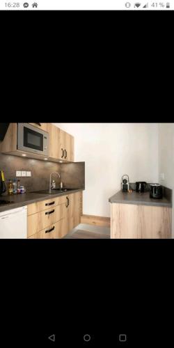 - une cuisine avec des placards en bois et un four micro-ondes dans l'établissement Appartement des cordeliers avec parking, à Albi