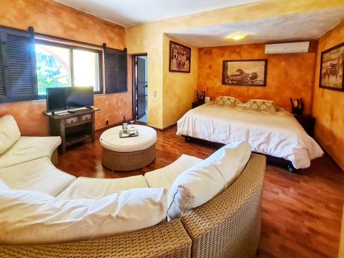 Habitación de hotel con 2 camas y sofá en Villa Paraiso - Naturism Optional Adults Only, en Porches