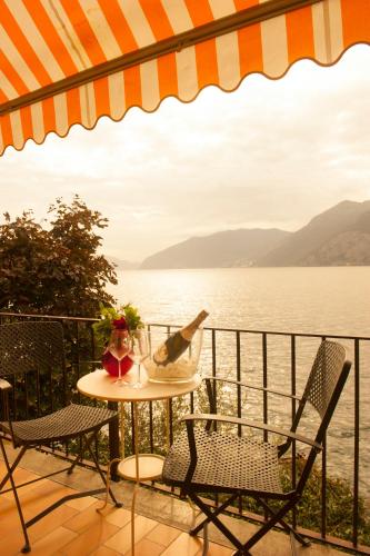 a table with a bottle of wine and chairs next to the water at Nest on The Lake in Marone