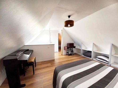 1 dormitorio con cama, escritorio y piano en Gîte Les Cerisiers, en Binic