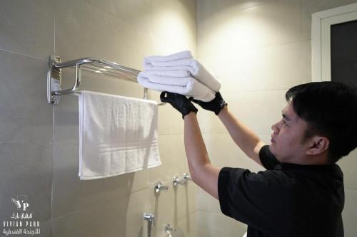 un homme tenant une pile de serviettes dans une salle de bains dans l'établissement فيفيان بارك العزيزية Vivian Park Al-Azizi, à Riyad
