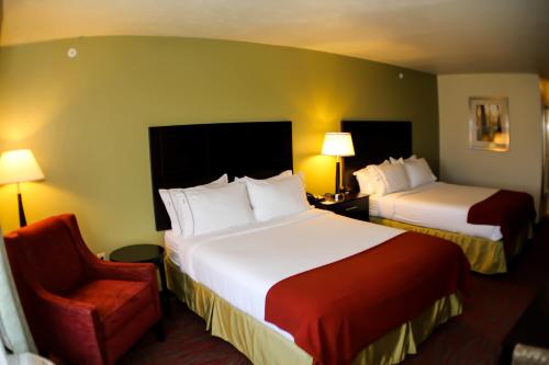 a hotel room with two beds and a chair at Holiday Inn Express & Suites Indianapolis North - Carmel, an IHG Hotel in Carmel