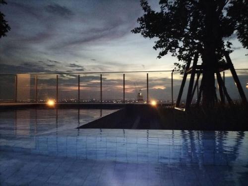 a view of a pool with a sunset in the background at Two bedroom condo with rooftop pool in Ban Talat Rangsit