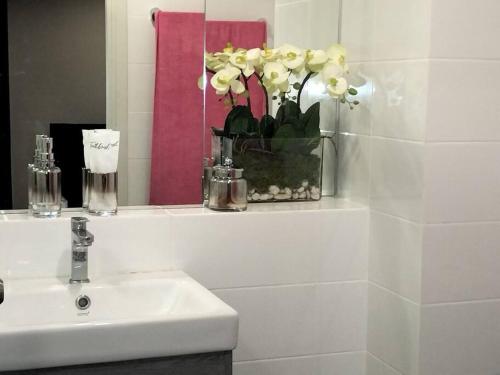 a bathroom with a sink and a vase of flowers at Two bedroom condo with rooftop pool in Ban Talat Rangsit