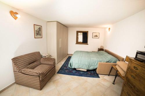 um pequeno quarto com uma cama e uma cadeira em Le Grand Coeur - Monolocale di montagna con stufa em Nus