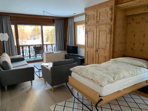 a bedroom with a bed and chairs and a balcony at Chesa La Furia in Pontresina