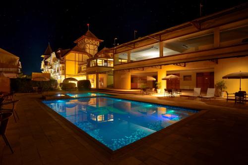 a swimming pool in front of a building at night at Hotel Le Renard - Campos do Jordao in Campos do Jordão