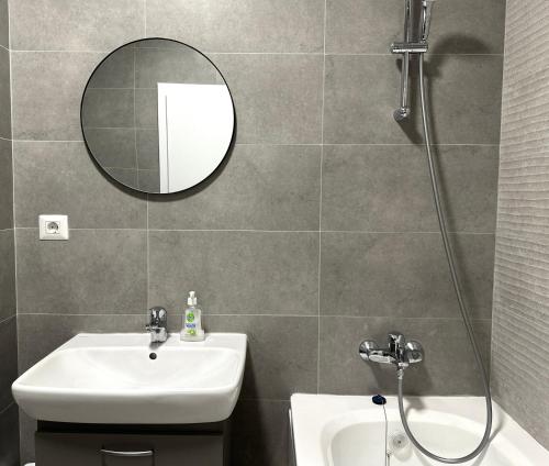 a bathroom with a sink and a shower with a mirror at Mrs Smart Luxury Apartament in Ploieşti