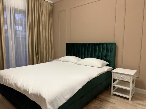 1 dormitorio con 1 cama grande y cabecero verde en Mrs Smart Luxury Apartament, en Ploieşti