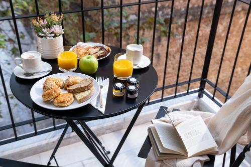 a table with a plate of food and two glasses of orange juice at Epoch House & The Orange Shop - Adults Only in Nafplio