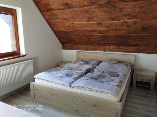 Cama en habitación con techo de madera en Chata pod lipou Bobrovník, en Bobrovník