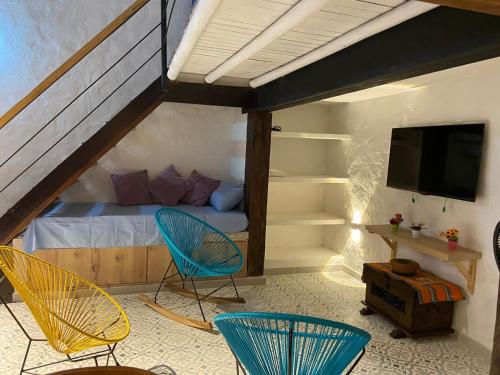 a bedroom with two chairs and a bed with a tv at Las 4 Estaciones Alojamientos de Ensueño Santorini Doradal in Puerto Triunfo