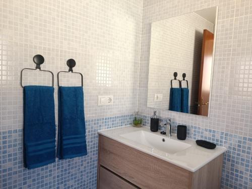 a bathroom with a sink and a mirror and blue tiles at Vista Volcán in Lajares