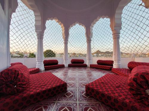 a room with red chairs and windows in a building at Hotel Kota kunj Heritage in Pushkar