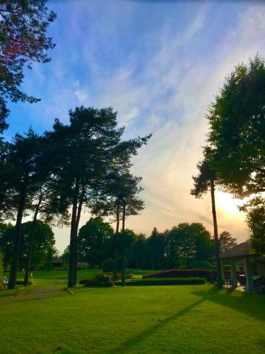 a field of grass with trees and a house at Golf Hotel La Pinetina in Appiano Gentile