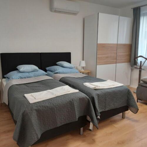 1 dormitorio con 2 camas y toallas. en Kis Ház Apartman, en Szigetvár