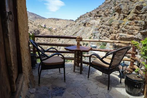 a table and chairs on a balcony with a view at the suwgra-Al-Jabal Al-Akdar in Sūkirah
