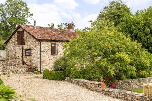 an old stone house with a stone wall at Holly Cottage in Honiton