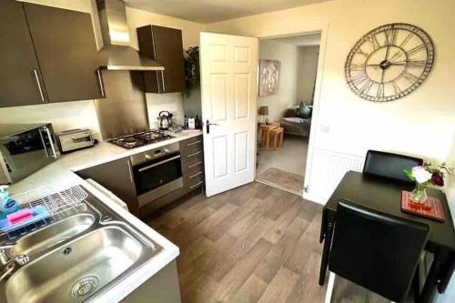 a kitchen with a sink and a clock on the wall at Loch Leven Getaway - 2 bed house in Kinross