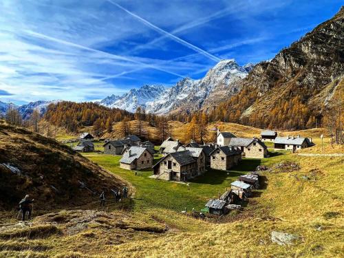 a village on a hill with mountains in the background at Appartamento vista Monte Rosa, giardino in Residence Walser a 10minuti da Macugnaga - MONTEROSAFLAT in Vanzone