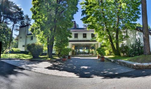 une maison blanche avec des arbres et une allée. dans l'établissement Golf Hotel La Pinetina, à Appiano Gentile