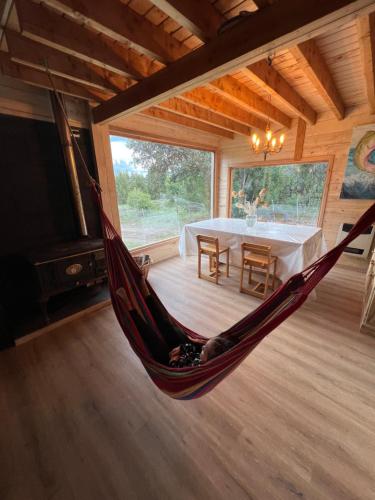 una hamaca en el medio de una habitación con una mesa en Cabaña Meliquina en Villa Meliquina