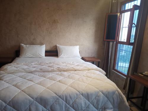 a white bed in a room with two windows at Durrat Al-Misfah Guest House in Misfāh