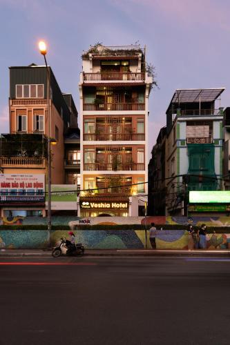 a person riding a motorcycle down a street with buildings at Veshia Hotel & Spa in Hanoi