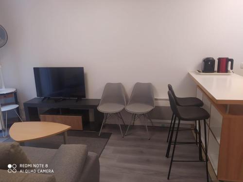 a room with three chairs and a table and a tv at Moderne & LUXURY T2 Paris la défense in Puteaux