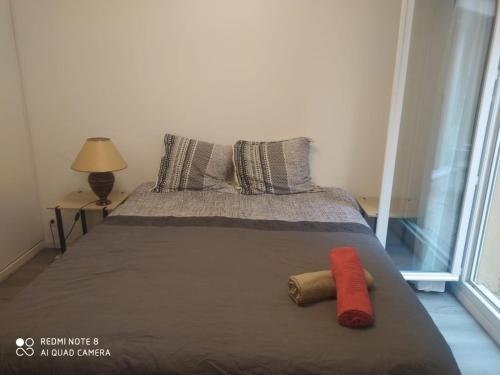 ein Bett mit zwei Kissen und einem roten Objekt darauf in der Unterkunft Moderne & LUXURY T2 Paris la défense in Puteaux