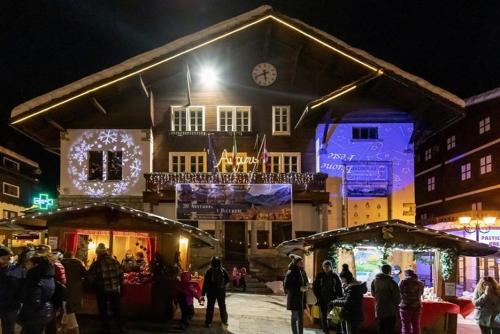 a group of people standing outside of a building at night at Appartamento vista Monte Rosa, giardino in Residence Walser a 10minuti da Macugnaga - MONTEROSAFLAT in Vanzone