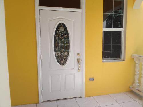 a white door with a round window on a yellow wall at Abigail's Sunflower Entire 2 Bedroom Apt in Tortola Island